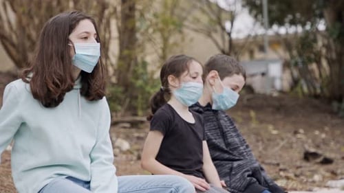 Coronavirus pandemic - kids wearing face masks to avoid contagion sitting bored