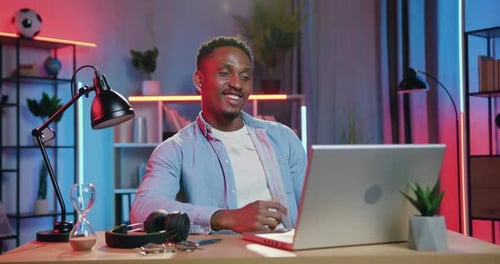 Chico de piel negra que está sentado frente a la computadora durante el chat de Vídeo