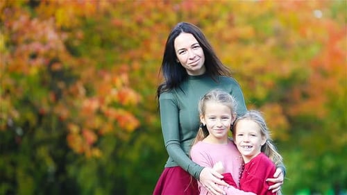 Mother Hugs Two Daughters in Autumn Park