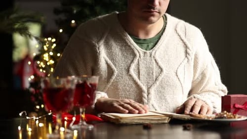 Man Reads at Christmas Table with Wine