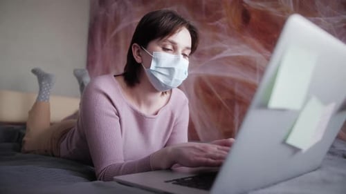Woman Working on Laptop Wearing a Surgical Mask