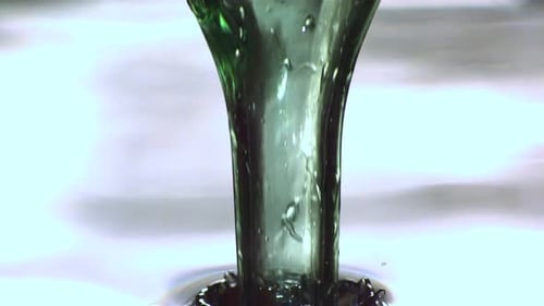 Glass Bottle Submerges into Water Creating Splash