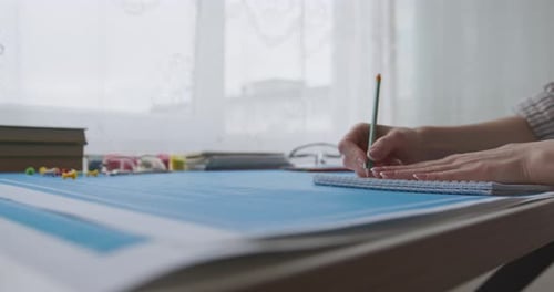 Designer Creating Plans at Desk Using Pencil and Ruler