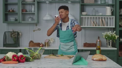 Young Adult Dancing with Phone While Cooking