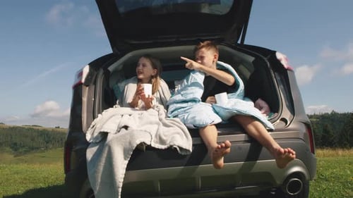 Kids Relaxing in Car Trunk Drinking Hot Beverage