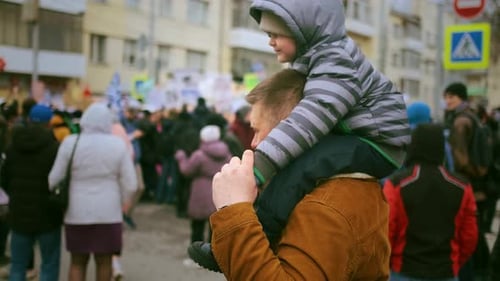 Father Carries Child on Shoulders Through Crowd