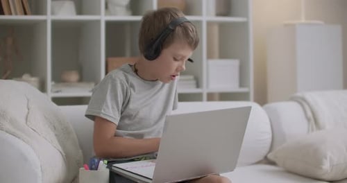 Boy Drawing with Laptop and Headphones at Home