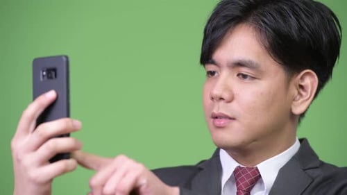 Young Adult Interacts with Smartphone on Green Screen