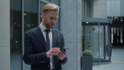 Man in Suit Using Smartphone in Modern Lobby