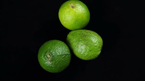 Three green limes on a black background