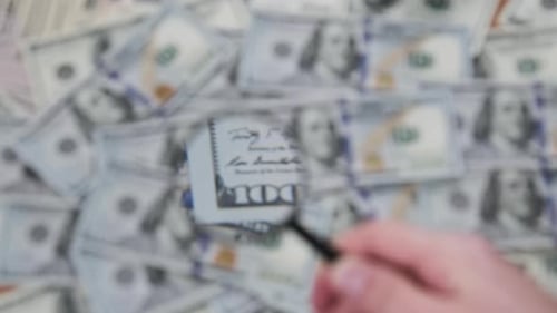 Examining One Hundred Dollar Bills with Magnifying Glass