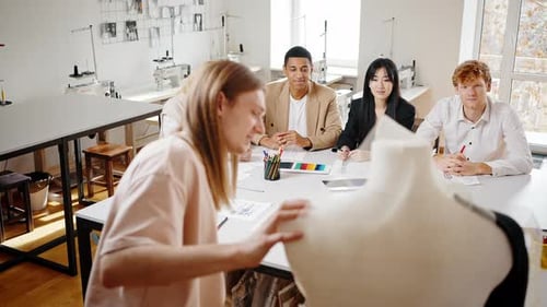 Gruppe von multiethnischen Menschen, die Meisterklasse beobachten Wie man Kleider kreiert Modedesigner-Putting