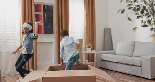 Happy Children Play with Cardboard Box at Home
