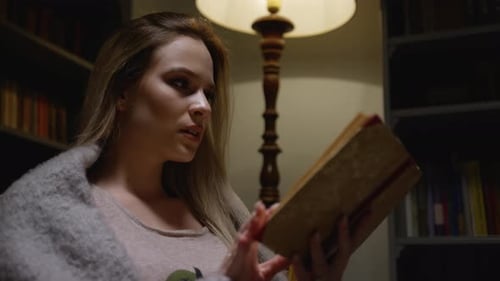 Woman Reading Book in Cozy Home Library at Night