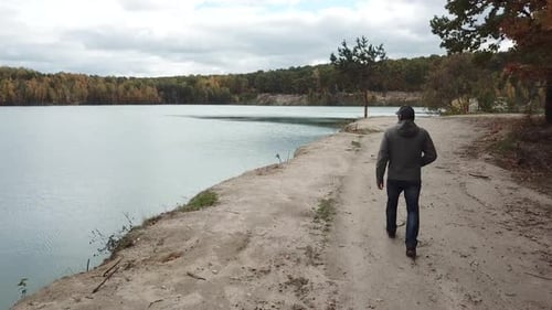 Mann geht auf der Natur. Luftaufnahme eines erwachsenen Mannes, der in der Nähe von Wald mit See geht
