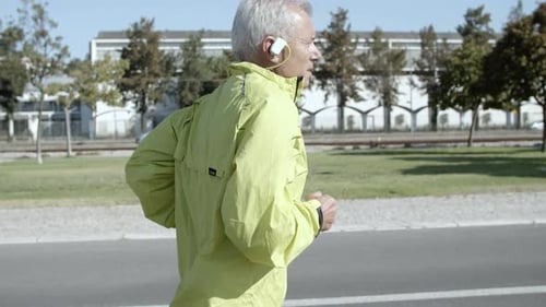 Senior Man Jogging on Urban Street With Headphones