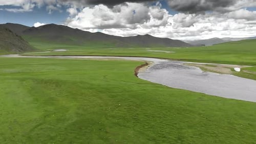 River Flowing Through an Empty Green Meadow with Unmanned and Treeless