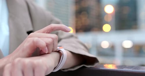 Woman Uses Smart Watch in City at Night