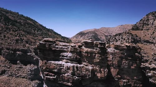 Drone volant de près au-dessus d'un rocher massif pour révéler une belle route routière reliant Mountain Canyon