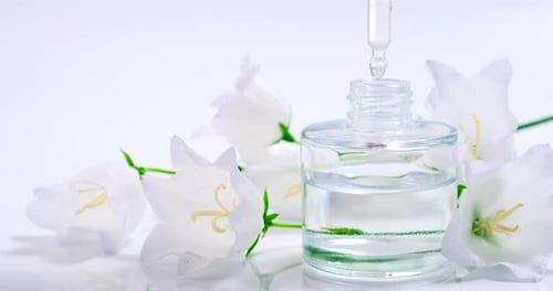 Produto de óleo essencial. Perfumaria. Gotas caindo da pipeta cosmética para o frasco de vidro com perfume