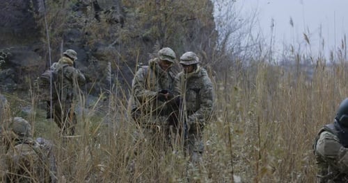 Soldiers Patrolling Field in Camouflage with Weapons