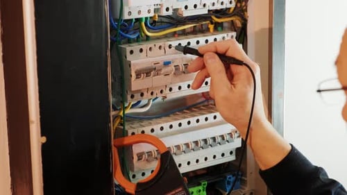 Elektriker testen den elektrischen Strom in der Schalttafel von Hand.