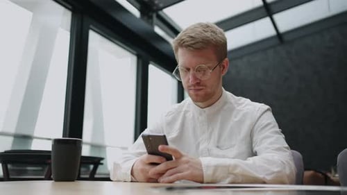 Man Using Smartphone at Modern Office Desk