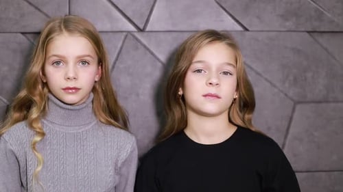 Two Cute Girls Posing in Front of Wall