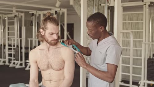 Man Getting Athletic Tape Applied at Physical Therapy