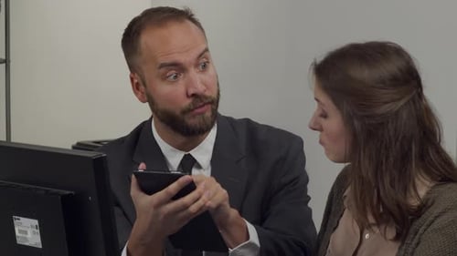 Male office worker works with female office worker discussing a project