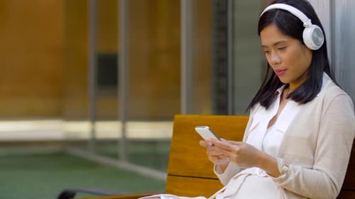 Young Adult Woman Using Smartphone with Headphones