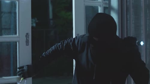 Burglar Jimmying Door at Night with Flashlight