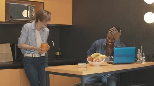 Woman and Man Chatting in Kitchen with Laptop