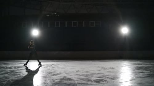 La jeune patineuse artistique porte des vêtements de sport noirs pour l"entraînement patine seule sur la patinoire à