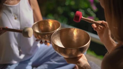 Women Playing Singing Bowls Outside in Daytime