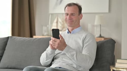 Man Using Smartphone Relaxing on Couch at Home