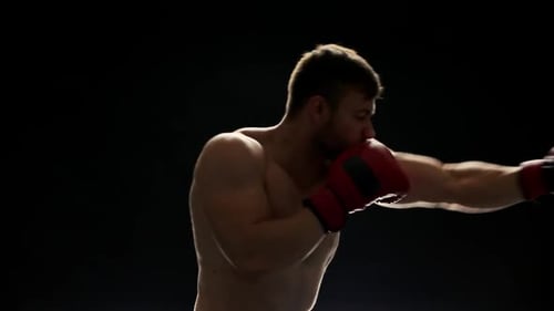 Shirtless Man Boxing in Dark Studio