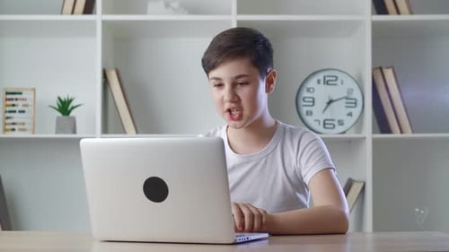 Teen boy video chatting on laptop at home