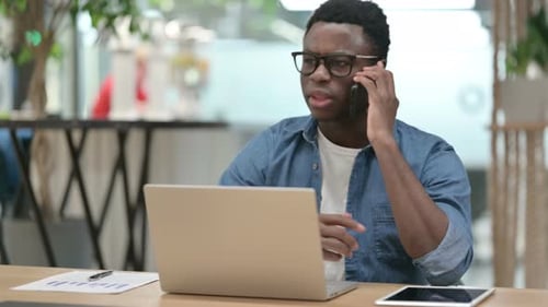 Young Adult Talking on Phone at Desk