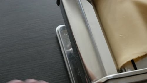 Dough Flattened by a Pasta Maker in Kitchen