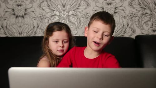 Children Watching Laptop Together on Couch Indoors
