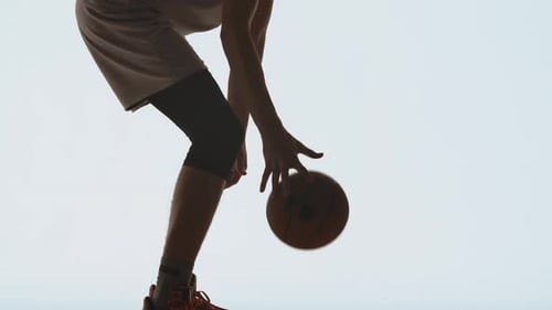 Silhouette d'un joueur de basket-ball en tenue de sport dribble ses compétences d'entraînement au ballon sur un studio blanc
