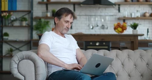 Man Relaxing on Sofa Using Laptop at Home