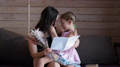 Affectionate Girl Giving Mother Handmade Card and Flowers