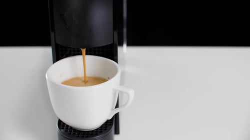 Close Up Pouring Hot Espresso with Steam From Coffee Machine To White Cup in Cafe. Professional