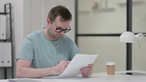 Young Man Reading Documents in Office