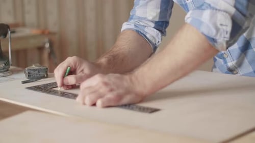 Man Measuring Wood Plank with Ruler in Workshop