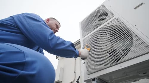 Technician Inspecting Air Conditioning Unit with Meter