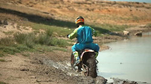Motorbike on Muddy Lake Shore Revs Engine