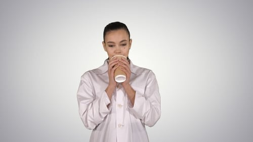 Young Adult Female in Lab Coat Drinks Coffee